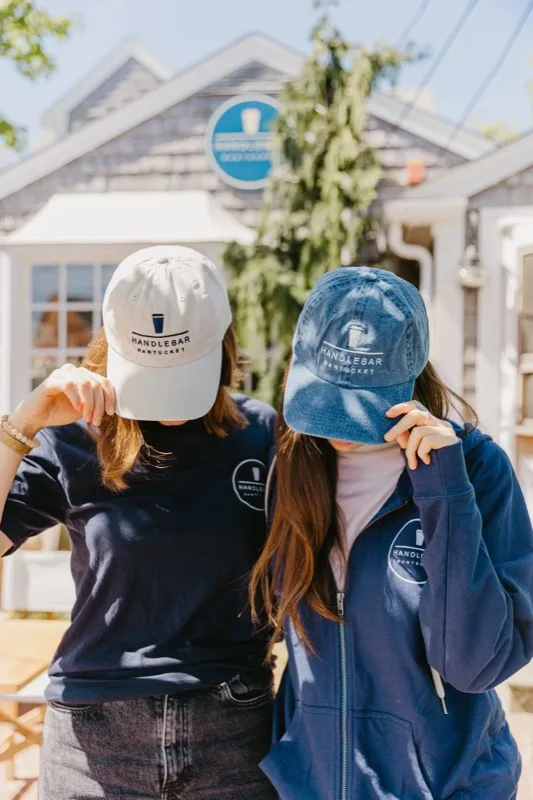 Two guests wearing Handlebar Nantucket hats in front of the café