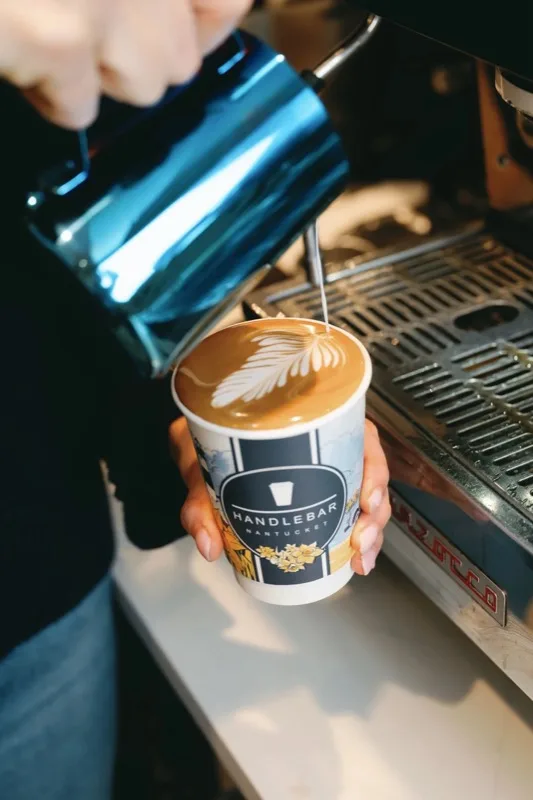 Barista pouring latte art into a Handlebar paper cup