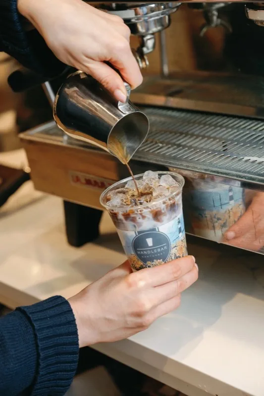 Barista pouring cream into an iced coffee